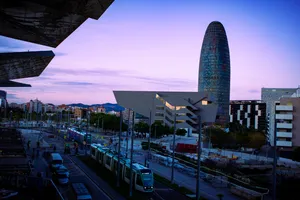 Two tramways crossing next to the Encants market, with the Glòries tower and the Disseny Hub behind.