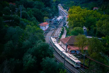 A FCC class 400 "frog" train arriving at les Planes station, from the FGC depot in Rubí, in the middle of the vegetation of the Collserola park. It's a three-car set with white-and-green carriages which, combined with the round front lights, make it resemble a frog.