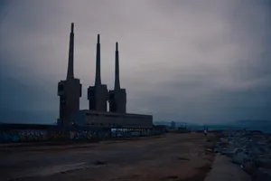 The "three chimneys" of Sant Adrià del Besòs. This used to be a thermal power plant that was operated by Endesa until 2011, when it was decommissioned. It consists of three identical chimneys side by side, with a height of 200 m, and a separate horizontal building which housed the turbines until they were dismantled. The power plant is located next to a beach and, while in operation, it polluted the surrounding environment and the water. There's some graffiti on the exterior walls of the complex.