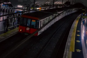 A white train with a red front entering and about to stop at Espanya station. There's a screen above the driver's compartment that says 124. The picture is a bit blurry.