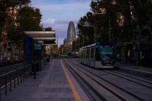 A tram about to leave Sicília stop, heading towards the north of the city. The Glòries tower, a rounded glass skyscraper that looks like a cucumber, is in the background.