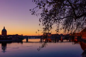 The sunset in Toulouse, captured from the Pont Neuf across the Garonne river, looking towards the Pont de Saint-Pierre, with the dome of the Hôpital de la Grave on the left.