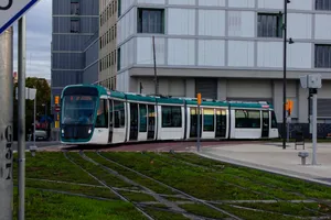 An Alstom Citadis X05 tram doing a test run on the Trambesòs network, in Barcelona. It's bending through an intersection near Glòries square.