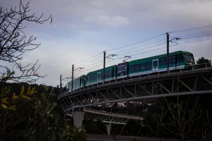 Two green Stadler GTW rack trains coupled together are crossing a tall bridge, around Monistrol de Montserrat.