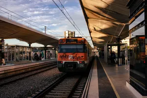 A graffitied Renfe 447 train about to leave Girona train station, on the afternoon.